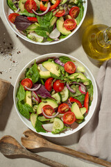 Vegetable salad with tomatoes, avocado and cucumber on a gray background