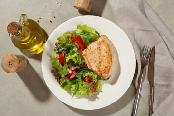 Salad with vegetables and chicken on a gray background