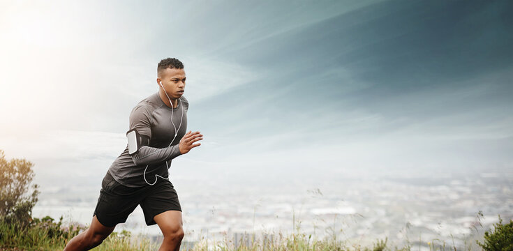 Man, running and space for fitness with cityscape for exercise, wellness or music with mockup for health. African male runner listening to audio for focus, workout and nature outdoor with mock up sky