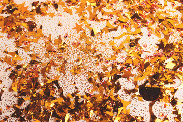 Shimmer golden confetti and glitter scattered on a beige background. Festive concept.