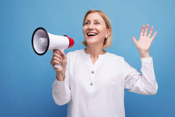 energetic mature woman with blond hair with loudspeaker announces important news with enthusiasm