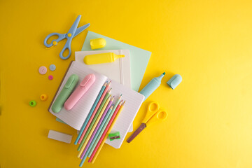 Flat lay of school supplies on yellow background with free space for text