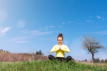 Woman doing yoga outdoors in countryside.