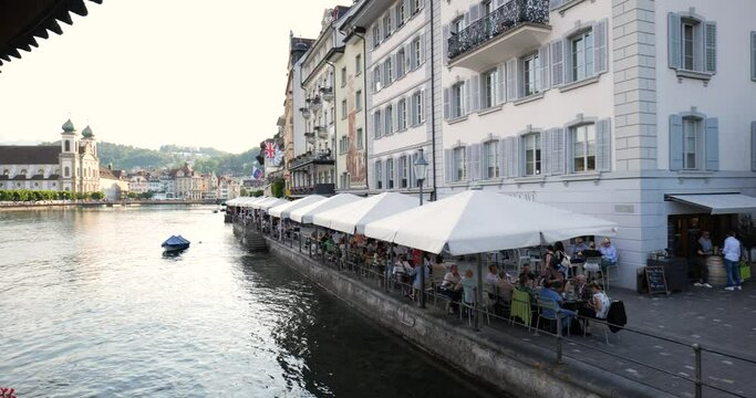 06-03-2023  Lucerne Switzerland. Medieval riverside building and cafe's as seen from the famous chapel bridge. Panning shot, real time