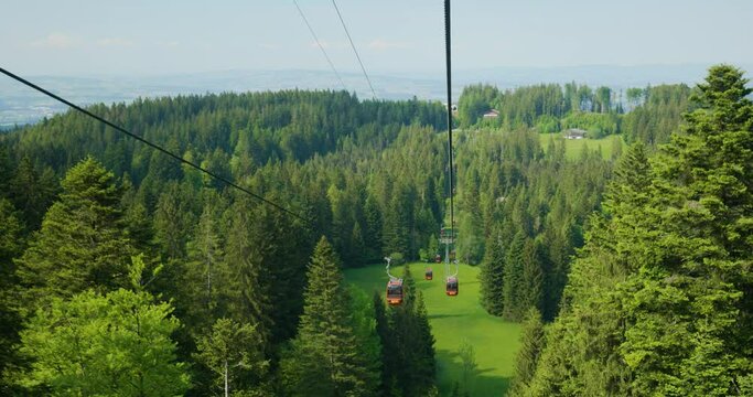 Funicular or cable car ride in the Swiss Alps. Green forest and pines trees, sunny day, red calbe cars, real time, no people