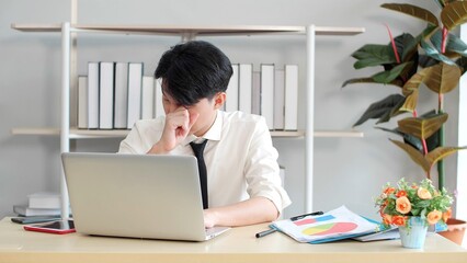 Young Asian man tired eyes from hard work. Young man tired feeling eyestrain stressed working from...