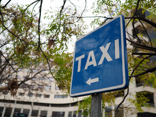 A blue taxi sign with an arrow pointing towards the direction of the taxi stand