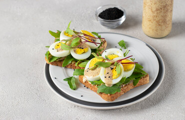 Homemade sandwiches with egg, arugula and cheese sprinkled with sesame seeds on round plate - obrazy, fototapety, plakaty