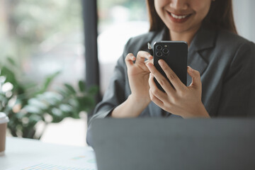 Woman holding a mobile phone and surfing the internet, executing apps on smartphone, answering emails and texting with colleagues. The concept of using technology in communication.