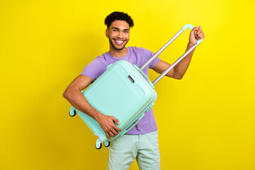 Photo of cheerful satisfied man toothy smile good mood arms hold suitcase isolated on yellow color background