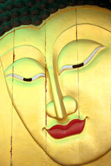 Golden Buddha image in thai style wood graving on the wall