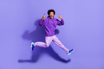 Fototapeta na wymiar Full size photo of positive crazy person wear stylish pullover jumping showing horns rock symbol isolated on purple color background