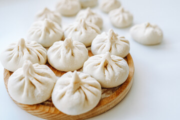 Khinkali sprinkled with flour on round wooden board