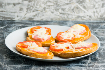 Delicious hot sandwiches with sausage, cheese and hot sauce, on white bread, on a gray plate