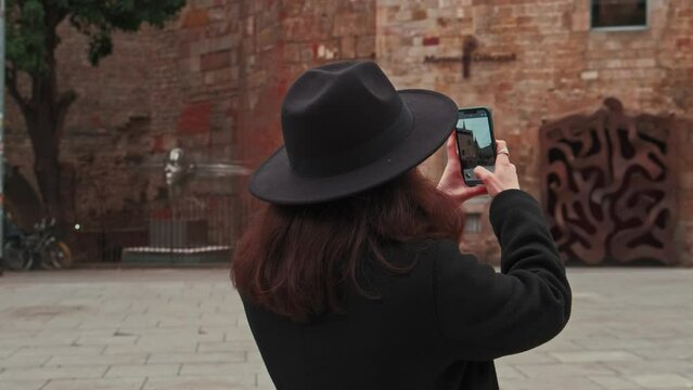 Slow motion footage of a woman taking a picture of a beautiful brick building in Barcelona. High quality 4k footage.