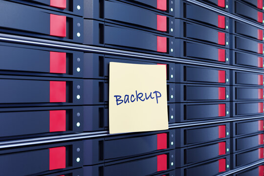 Yellow sticky note written with the word Backup stuck on stacks of server NAS devices. Illustration of the concept of cloud backup and routine backup procedures