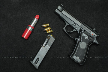 Women's small pistol 9mm and red lipstick on a black sofa.