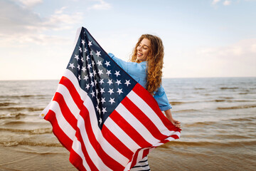 Young woman with  American flag on the beach. Patriotic holiday. USA celebrate 4th of July....