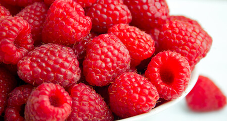 juicy raspberries stacked in a white bowl