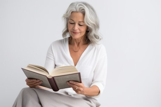 Lifestyle portrait photography of a tender mature woman reading a book against a white background. With generative AI technology