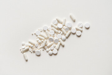 Scattered white pills on a white table. Mock up for special offers as advertising, web background or other ideas. Medical, pharmacy and healthcare concept. copyspace. Empty place for text or logo - obrazy, fototapety, plakaty