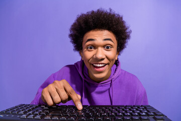 Portrait of funky optimistic person wear violet hoodie typing meesage on keyboard look at display isolated on purple color background