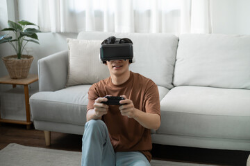 Obraz premium Young Asian man gamer wearing virtual reality touching air during the VR experience Future home technology player hobby playful enjoyment concept.