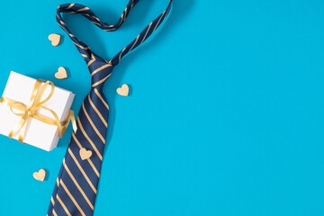 Obraz na płótnie Canvas Father's Day concept. Flat lay top view of necktie, gift box and hearts on blue background with space for text or promotion and greeting message