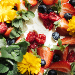 Meringue cake background. Top view cake. Fruit decorations. Red strawberries and raspberries on Pavlova whipped cream cake. Sweet dessert round cake. Decorated with berries. Yellow flowers.