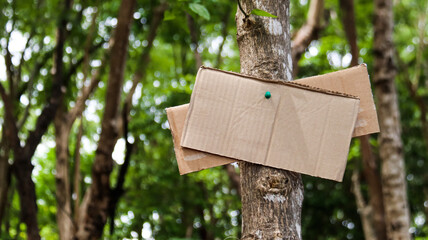 Blank brown paper sign on a tree trunk, concept for forests and environment saving and preservation...