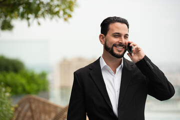 Portrait of handsome businessman outdoors at rooftop talking on mobile phone - 611011993
