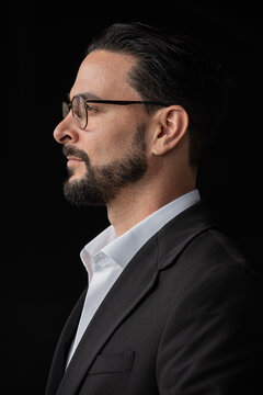 Profile view portrait of handsome businessman against black background wearing eyeglasses