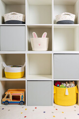 Obraz na płótnie Canvas White shelving with colorful storage baskets and boxes with toys. Interior design. Organizing and storage ideas in children room. Interior design. Playroom
