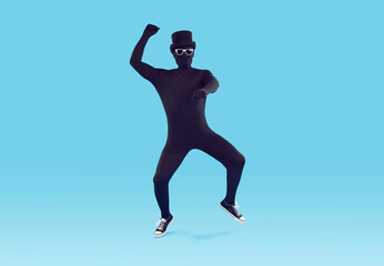 Fototapeta na wymiar Mysterious faceless man dressed in black bodysuit dancing. Full length portrait of disguised man wearing full body spandex costume, bowler hat and sunglasses having fun over isolated studio background