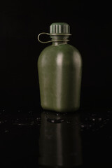 flask plastic army green not new on a black background with reflection and water droplets. Side view