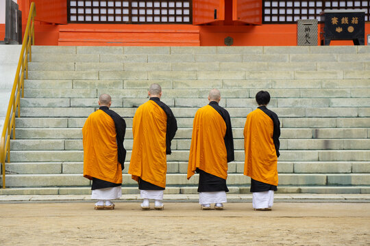 Japanese Buddhist Monks wearing traditional orange Robe stanning in front of Temple at Mount Koya, Japan