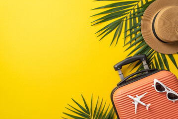 Tropical journey concept. Top view photo of orange suitcase with airplane model and sunglasses on it surrounded by palm leaf and straw hat on isolated bright yellow background with copy-space