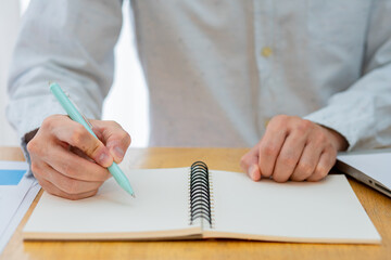 Closeup worker planning with pen, notes and schedule of information in journal, reports or logistics agenda, strategy and online data analysis at desk. Worker, computer and notebook