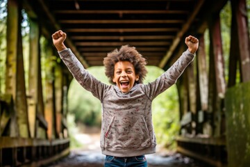 Environmental portrait photography of a happy kid male celebrating with his fists against a rustic bridge background. With generative AI technology