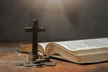 Stack of coin money, holy bible book and old wallet on wooden table. Copy space, a closeup. Christian biblical concept of tithing, giving, and religious offering..