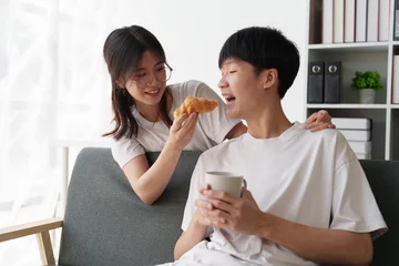 Beautiful asian couple in love and smiling sitting on sofa at morning. Romantic moment, relationships, family concept © itchaznong