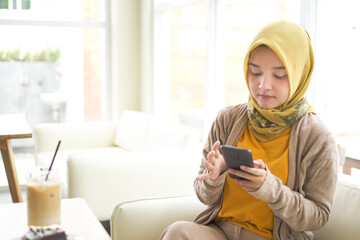 Business asian hijab woman wearing Orange T-shirt holding mobile phone