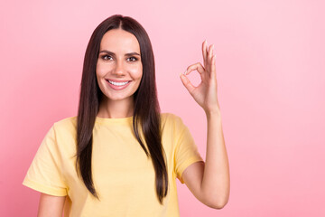 Photo of pretty confident lady wear yellow t-shirt showing okey gesture empty space isolated pink color background