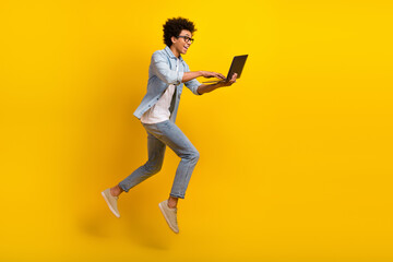 Fototapeta na wymiar Full size profile portrait of excited crazy guy jump rush use netbook isolated on yellow color background