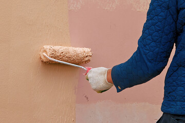 Worker renovate facade. Painting wall with paint roller. Industrial painter at work. Worker...