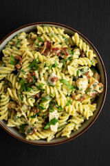 Homemade Chicken Spinach Alfredo Rotini Pasta in a Bowl on a black background, top view. Flat lay, overhead, from above.