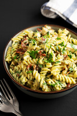 Homemade Chicken Spinach Alfredo Rotini Pasta in a Bowl on a black background, side view.
