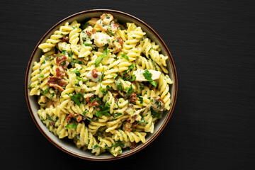 Obraz na płótnie Canvas Homemade Chicken Spinach Alfredo Rotini Pasta in a Bowl on a black background, top view. Flat lay, overhead, from above. Copy space.