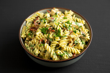 Homemade Chicken Spinach Alfredo Rotini Pasta in a Bowl on a black background, side view.