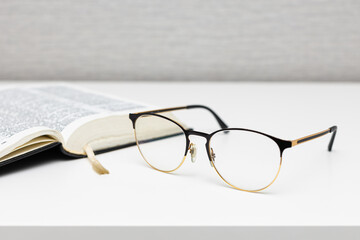 reading glasses lie on the table near the book.